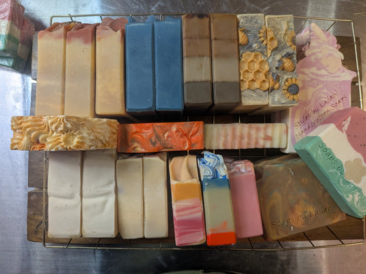 Assorted bars of soap in various colors and designs on a metal rack.