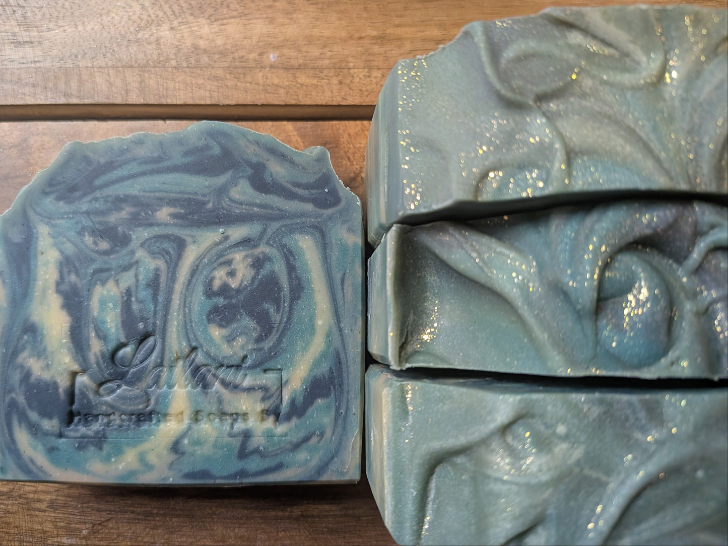 Two bars of blue soap with decorative patterns on a wooden surface