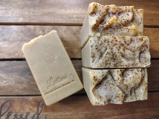 Three bars of soap with visible branding on a wooden surface