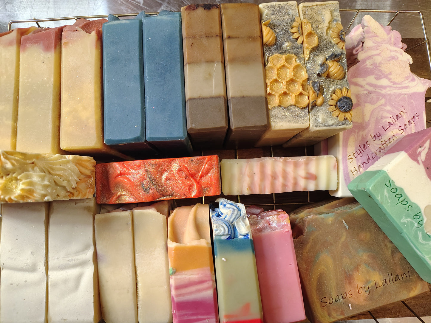 Assorted bars of soap with various colors and designs on a wooden surface.